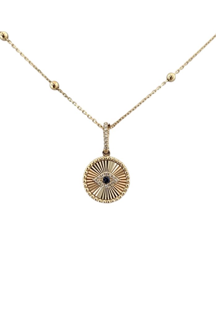 Gold necklace with a round sunburst medallion pendant featuring a pavé evil eye center and small beaded chain accents, shown on a white background.