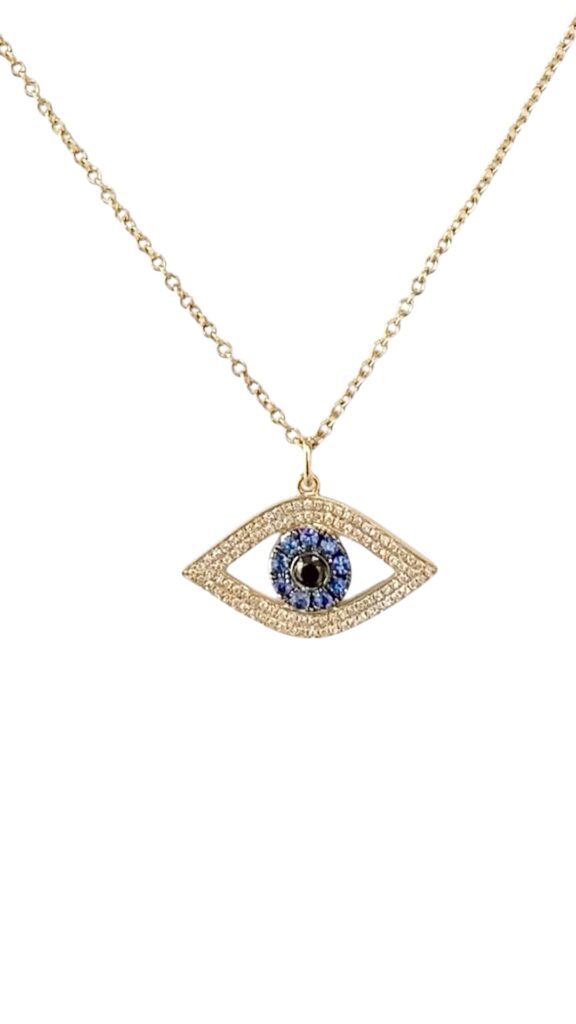 Gold necklace with an evil eye pendant featuring pavé diamonds, a halo of blue sapphires, and a dark center stone, photographed on a white background.