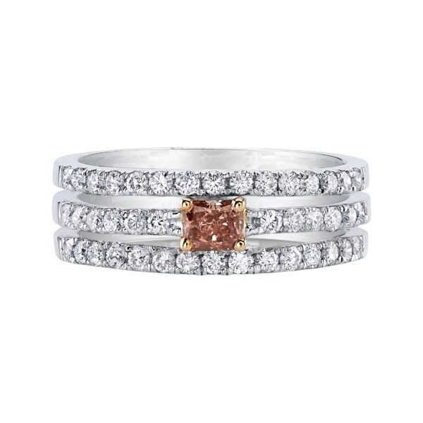 Platinum ring with three rows of round white diamonds and a deep pink cushion-cut center diamond set in yellow gold prongs.