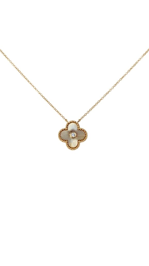 Gold necklace with a four-leaf clover-shaped pendant featuring a sunburst texture and center stone, photographed on a white background.